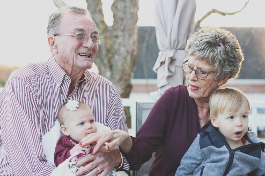A grandmother and grandfather tend to their two young grandchildren.
